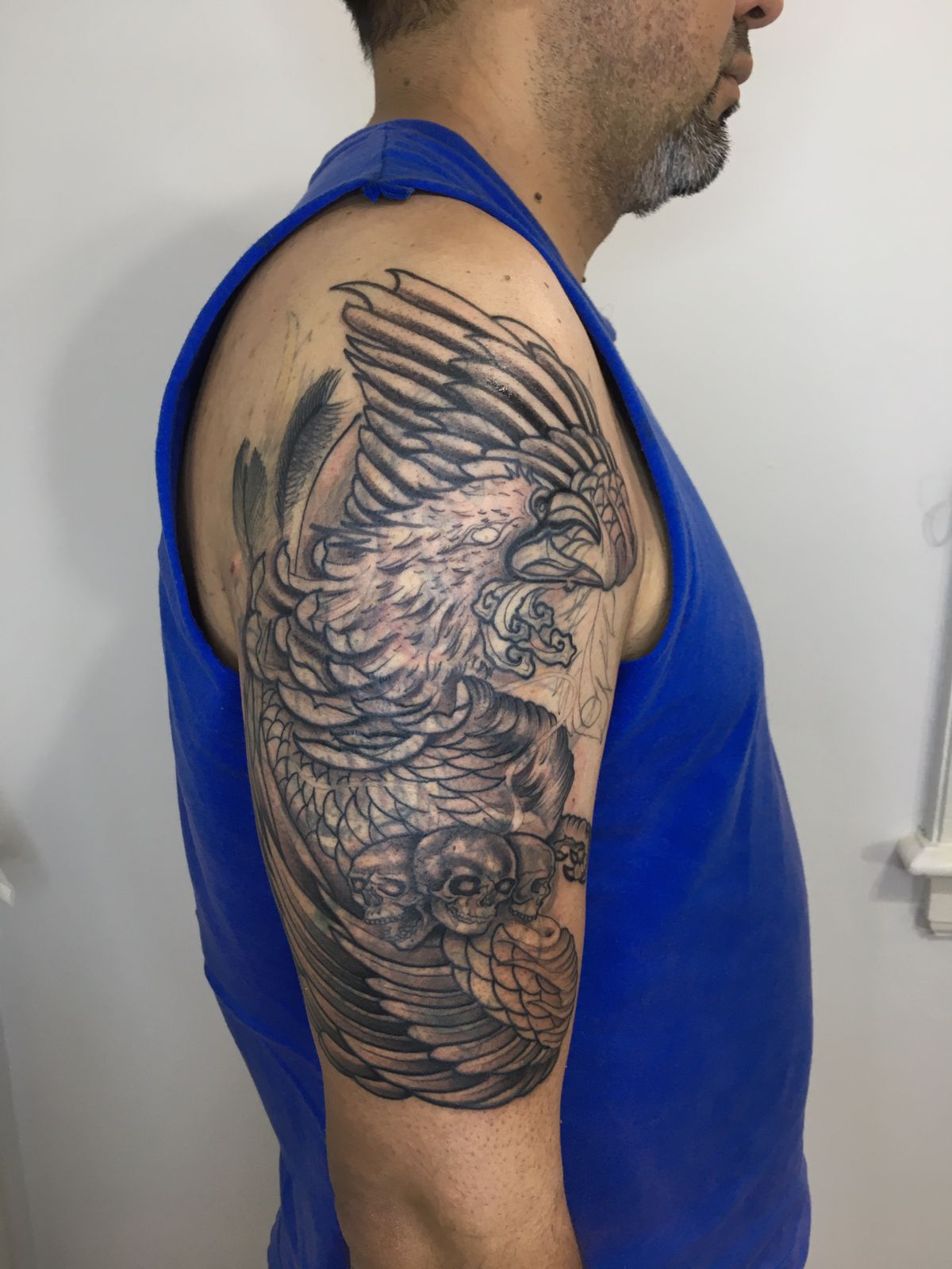 Tatuaje de águila y calaveras en brazo